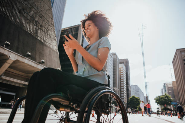 wheelchair woman on the street using smartphone - outdoor lifestyle imagens e fotografias de stock