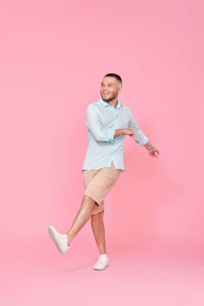 istock cheerful young happy man dance on pink background. 1408889075