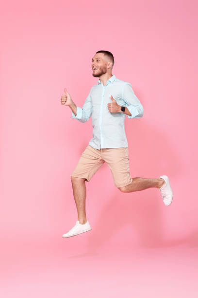 istock man in summer clothes jumping on pink background. 1408889085