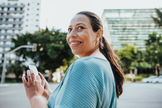 mulher usando um smartphone  - mature women outdoors smiling happiness - fotografias e filmes do acervo