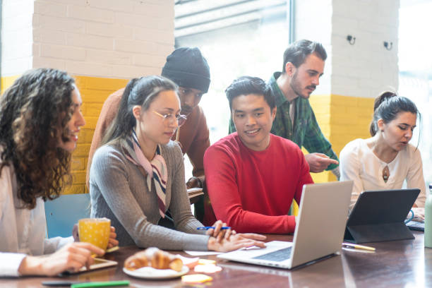Young co-workers multiethnic team planning a new startup - Happy people working on a new project in creative coworking office - Marketing concept - Bright filter with focus on asian man face