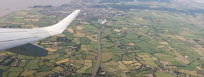 Horizontal banner or header with aerial View of Bristol City Center in England, UK  and surrounding fields. On the left the airplane wing