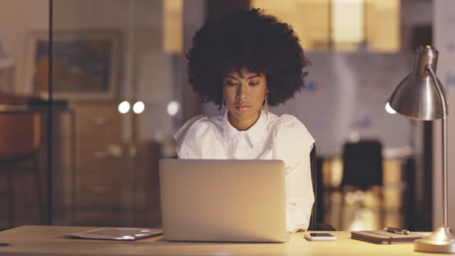 Businesswoman working on laptop late at night. Female entrepreneur checking and sending emails. Business professional browsing online on computer. Employee working overtime trying to meet a deadline