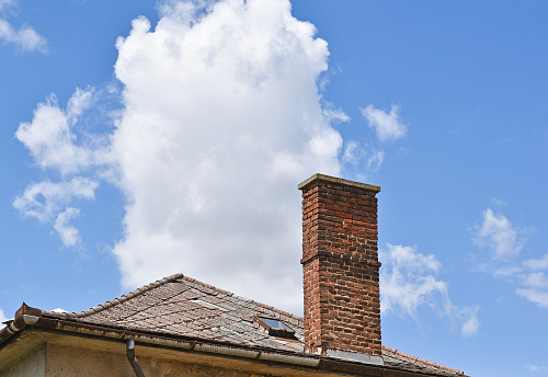 An old abandoned house in poor condition. Much of the roof is missing, and there is no glass in the windows. It looks like it will fall over soon.