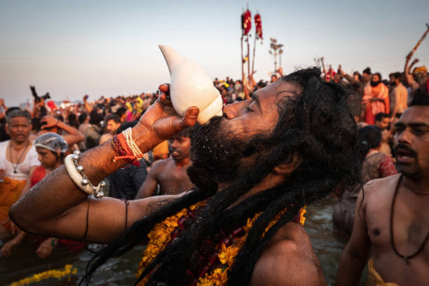 naga sadhu bläst beim kumbh mela festival in allahabad (prayagraj), uttar pradesh, indien in eine muschelschale - devotee stock-fotos und bilder