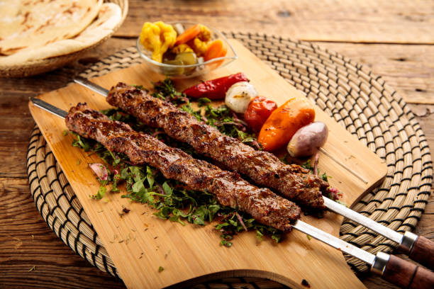 Adana Kebab served in a wooden cutting board isolated on wooden background side view stock photo