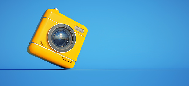 3D rendering of a yellow camera against a blue background with lots of copy space