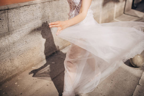 Beautiful young female is an elegant wedding dress walking on sidewalk outdoors in city.