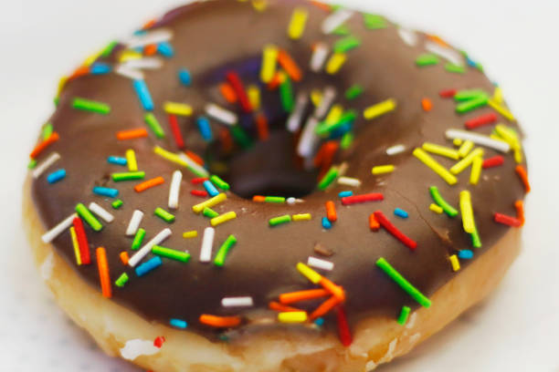 istock chocolate coated doughnut or donut with sprinkles on in close up 1408898809