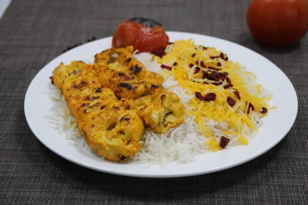 Photo of Joojeh Kebab with rice served in a dish isolated on wooden background side view