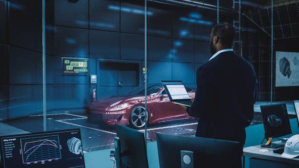 istock Engineering Research Agency Perform Aerodynamic Testing with a Modern Eco-Friendly Electric Sports Car in a Wind Tunnel. Professional Scientist Works on a Laptop Computer and Changes Testing Options. 1408904776