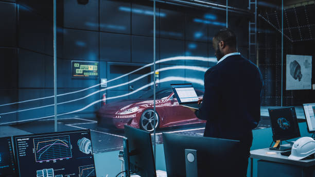 istock Engineering Research Agency Perform Aerodynamic Testing with a Modern Eco-Friendly Electric Sports Car in a Wind Tunnel. Professional Scientist Works on a Laptop Computer and Changes Testing Options. 1408904803