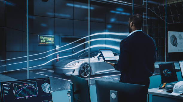istock Engineering Research Agency Perform Aerodynamic Testing with a Modern Eco-Friendly Electric Sports Car in a Wind Tunnel. Professional Scientist Works on a Laptop Computer and Changes Testing Options. 1408904845