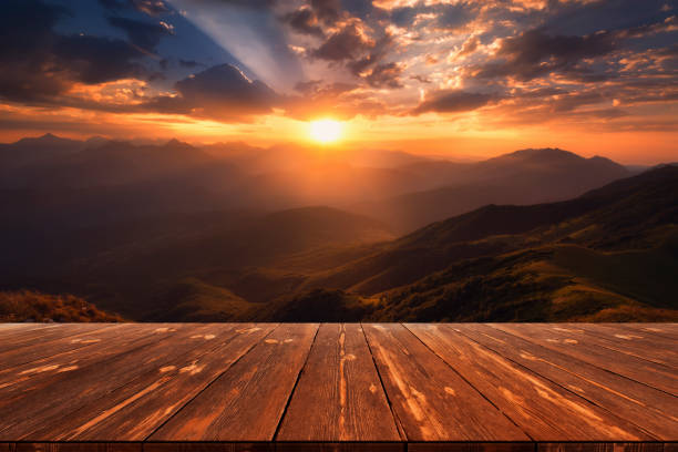 istock Rays of light pass through the clouds, beautiful mountain landscape with empty wooden table 1408906238