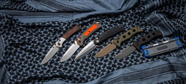 Various pocket knives with retractable blades. Light fabric background.