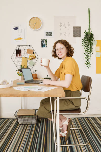 istock Happy young female freelance accountant with cup of tea or coffee making notes 1408908695