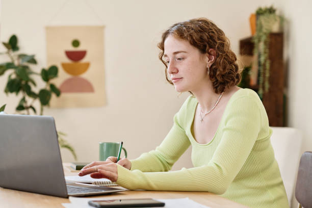 istock Young confident businesswoman making notes while working in front of laptop 1408909347