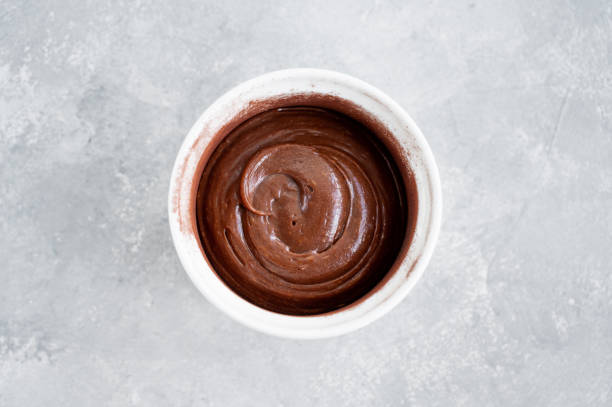 istock Raw dough for making chocolate lava cake in a baking dish on a gray concrete background. Recipe step by step. Top view. 1408912873