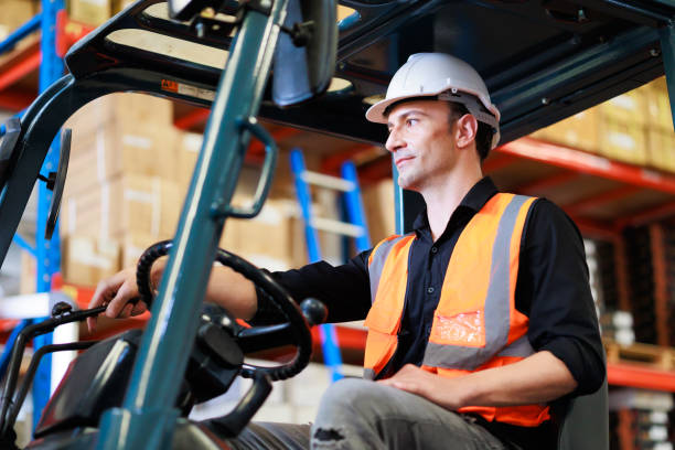 istock Caucasaian man Warehouse staff driving forklift operator moving boxes in industrial container warehouse factory. Man worker woking with forklift. 1408912912