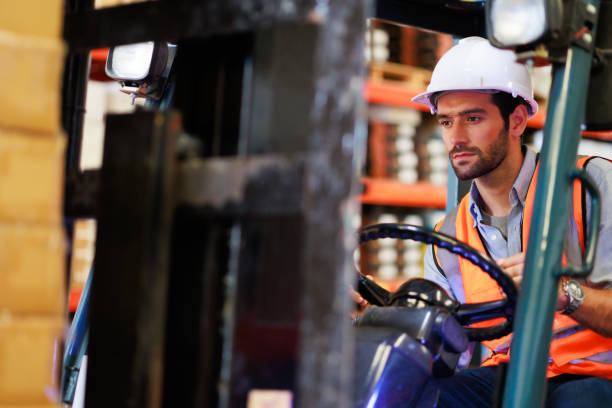 istock Warehouse staff driving forklift operator moving boxes in industrial container warehouse factory. Man worker woking with forklift. 1408913016