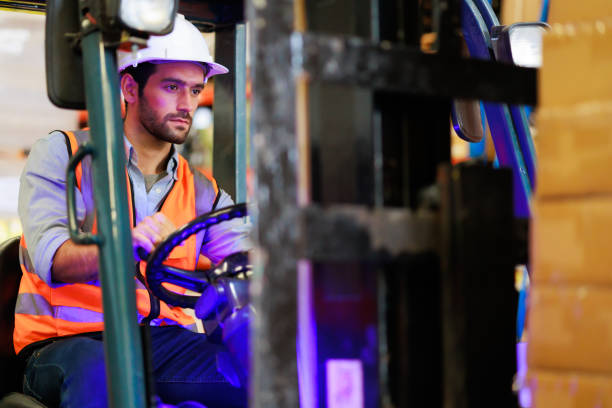 istock Warehouse staff driving forklift operator moving boxes in industrial container warehouse factory. Man worker woking with forklift. 1408913020