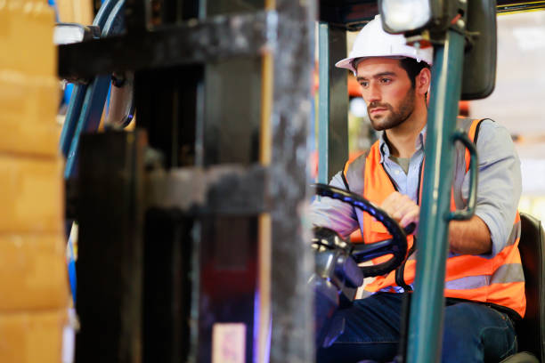 istock Warehouse staff driving forklift operator moving boxes in industrial container warehouse factory. Man worker woking with forklift. 1408913031