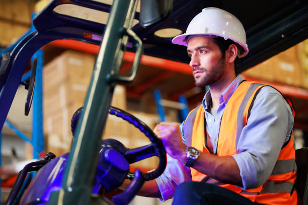 istock Warehouse staff driving forklift operator moving boxes in industrial container warehouse factory. Man worker woking with forklift. 1408913046
