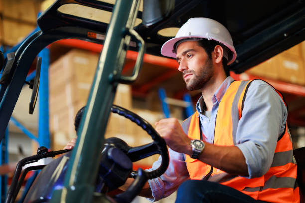istock Warehouse staff driving forklift operator moving boxes in industrial container warehouse factory. Man worker woking with forklift. 1408913050