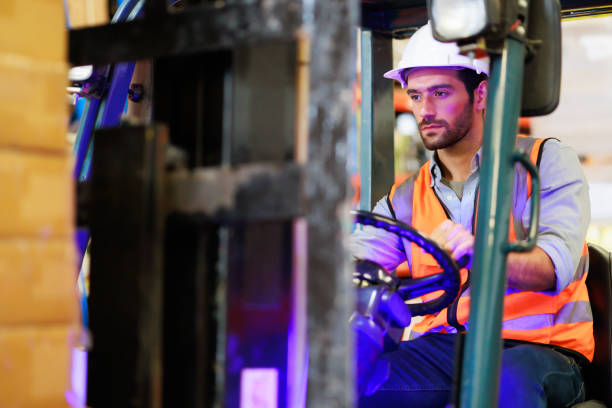 istock Warehouse staff driving forklift operator moving boxes in industrial container warehouse factory. Man worker woking with forklift. 1408913054