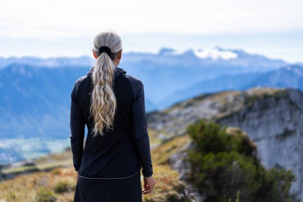 istock Back view of woman alone in blurry mountain background 1408913348