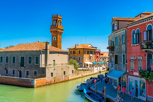 Murano, Venice - Italy July 6, 2022. View of canal with Clock Tower at background in Murano. Venice, Italy