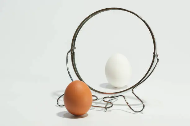 White and brown eggs reflected in the mirror on the white background.