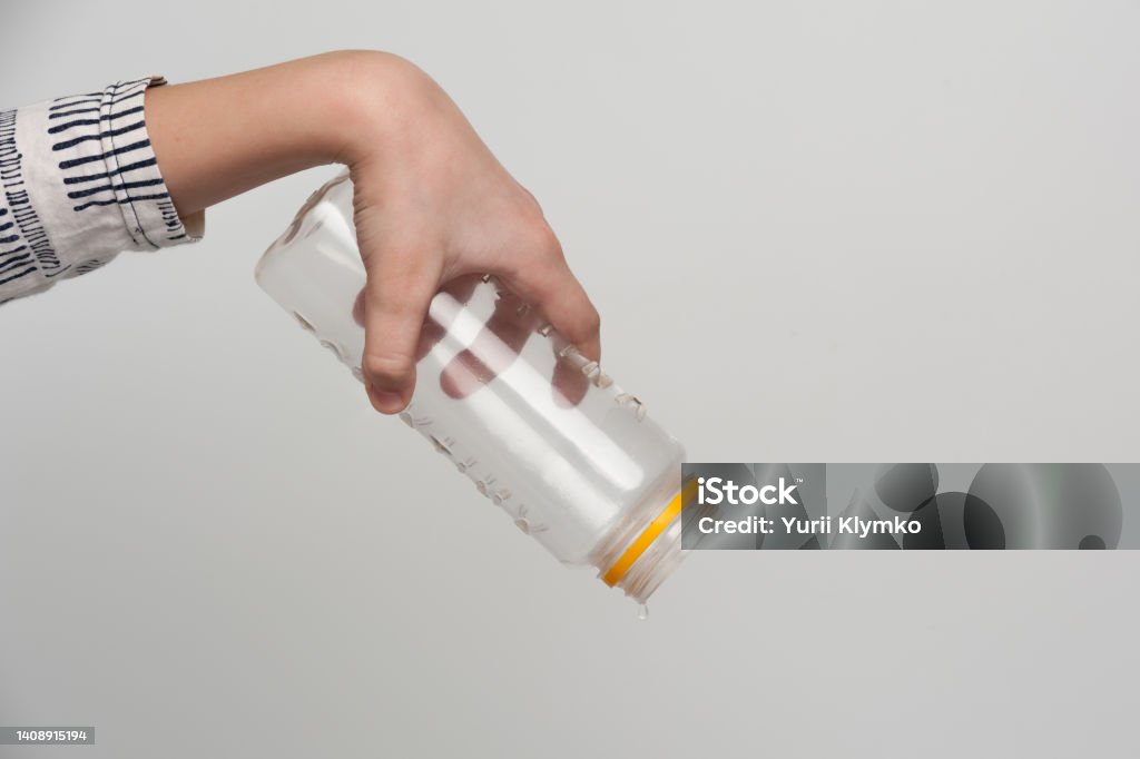 human hands holding an empty bottle The human hand holding an empty plastic bottle pouring out the last drop of water Empty Stock Photo