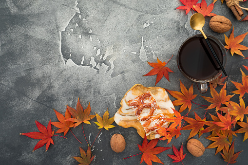 Autumn frame composition. Fall maple leaves with walnuts, cup of coffee and resin art plate on stone background. Autumnal thanksgiving day concept. Flat lay, top view