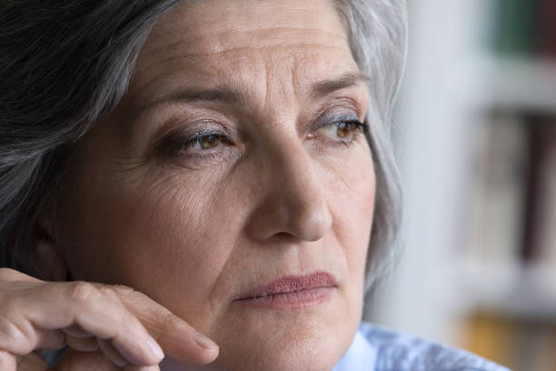 istock Pensive mature grey haired lady looking away in deep thought 1408920956