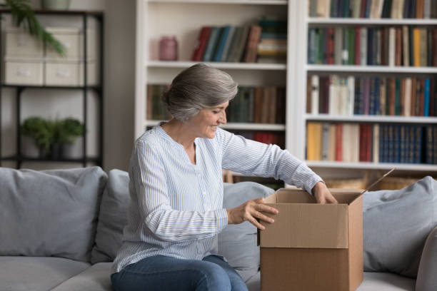 istock Happy elderly grey haired customer woman unpacking parcel at home 1408920985