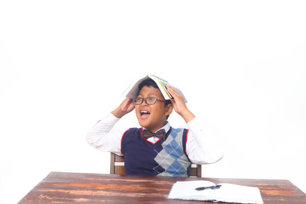 Asian school boy with book on head. Isolated on white background