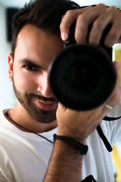 istock Handsome brown-haired guy with a beard, taking pictures of himself in a mirror because it is the photography day. 1408921528