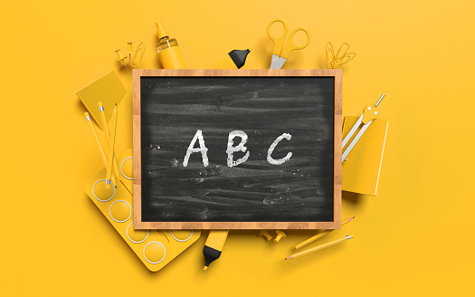 Back to School ABC alphabet concept with school equipment behind a blackboard against yellow orange background. Educational concept. Easy to crop for all your design and print needs.