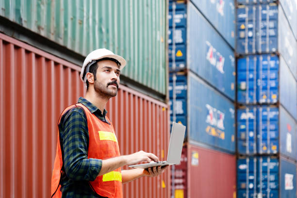 istock Container workers use laptops to work in port warehouses. Wear a hardhat to be safe at work. 1408922866