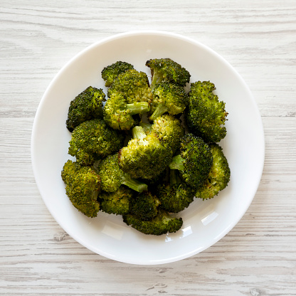 Homemade Roasted Broccoli with Salt and Pepper on a plate on a white wooden background, top view. Flat lay, overhead, from above.
