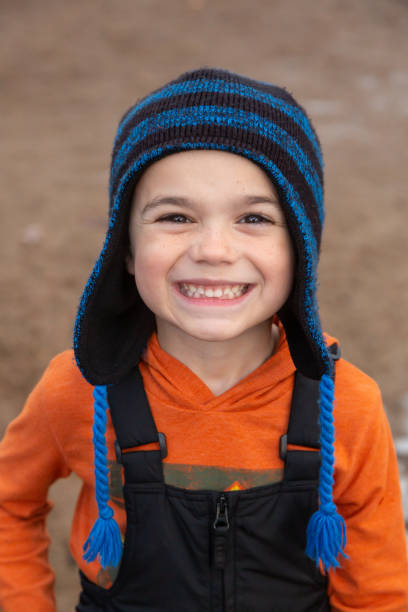 Close-up of a young boy at the beach on a winter day. He is smiling at the camera.