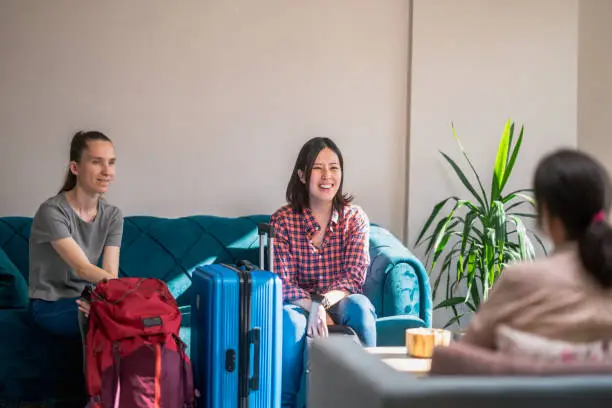Photo of Host-mother welcoming to multi-ethnic female tourists to her house and talking together in living room