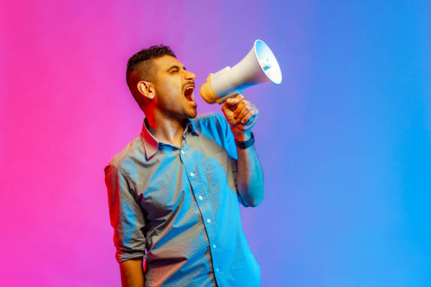 istock Man in shirt screaming at megaphone, making announce, protesting, looking away with angry expression 1408928499
