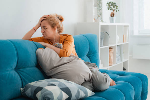 несчастная одинокая депрессивная женщина дома, она сидит на диване, прячет подушку для лица, концепция депрессии - women crying distraught thinking стоковые фото и изображения