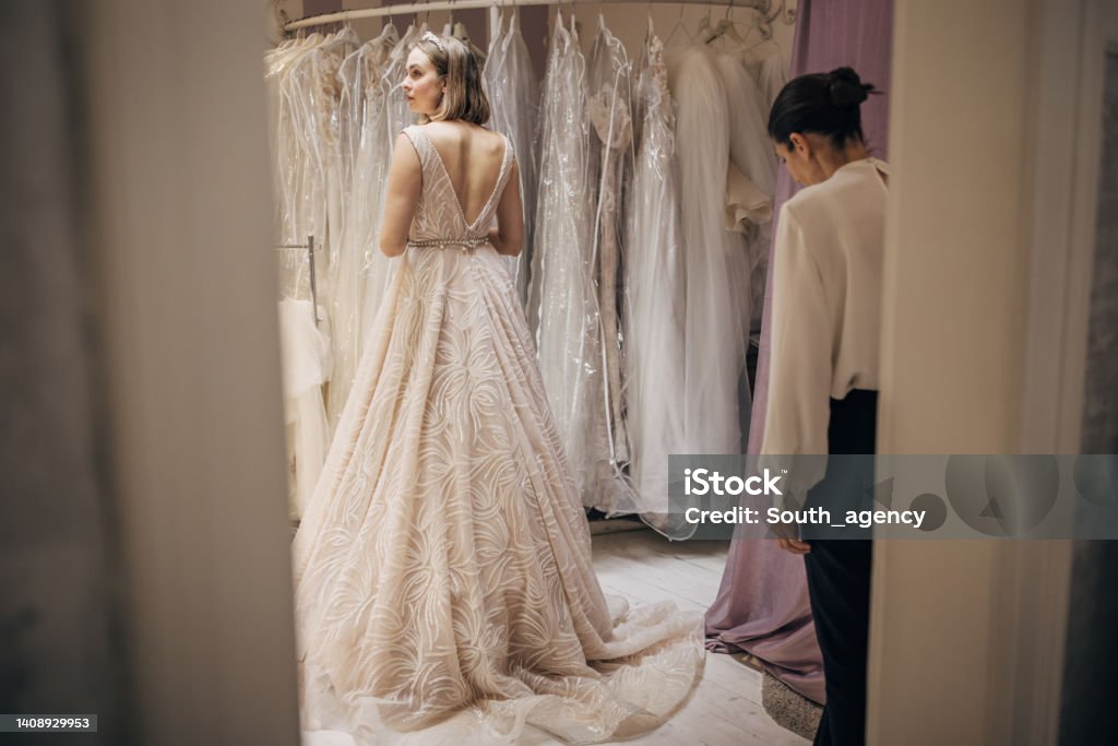 Woman trying on a wedding dress Beautiful young female is trying on an elegant wedding dress in bridal shop. Wedding Dress Stock Photo