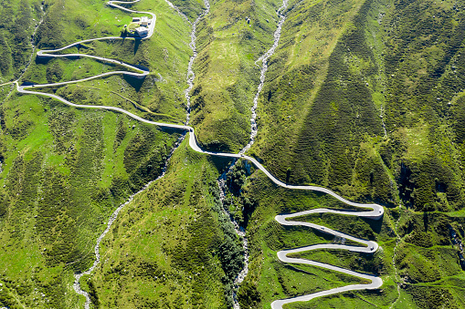 Directly from above view of a winding mountain road with car traffic, Splügen Pass, Graubunden Canton, Swiss Alps.