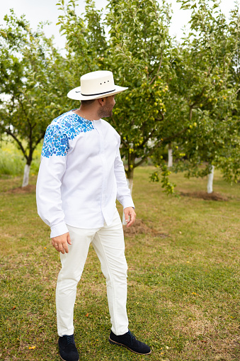 Man in a white shirt walks through an apple orchard