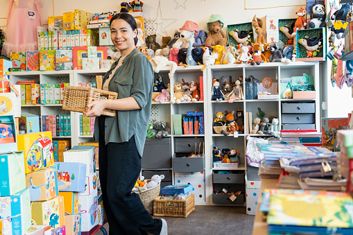 Wide view of young female Latin-American shop owner standing in her toy store