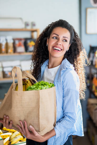 アフリカ系アメリカ人の若い女性の成功した起業家が、オーガニック食料品店での仕事中に微笑んでいる中盤のショット - 2503 ストックフォトと画像